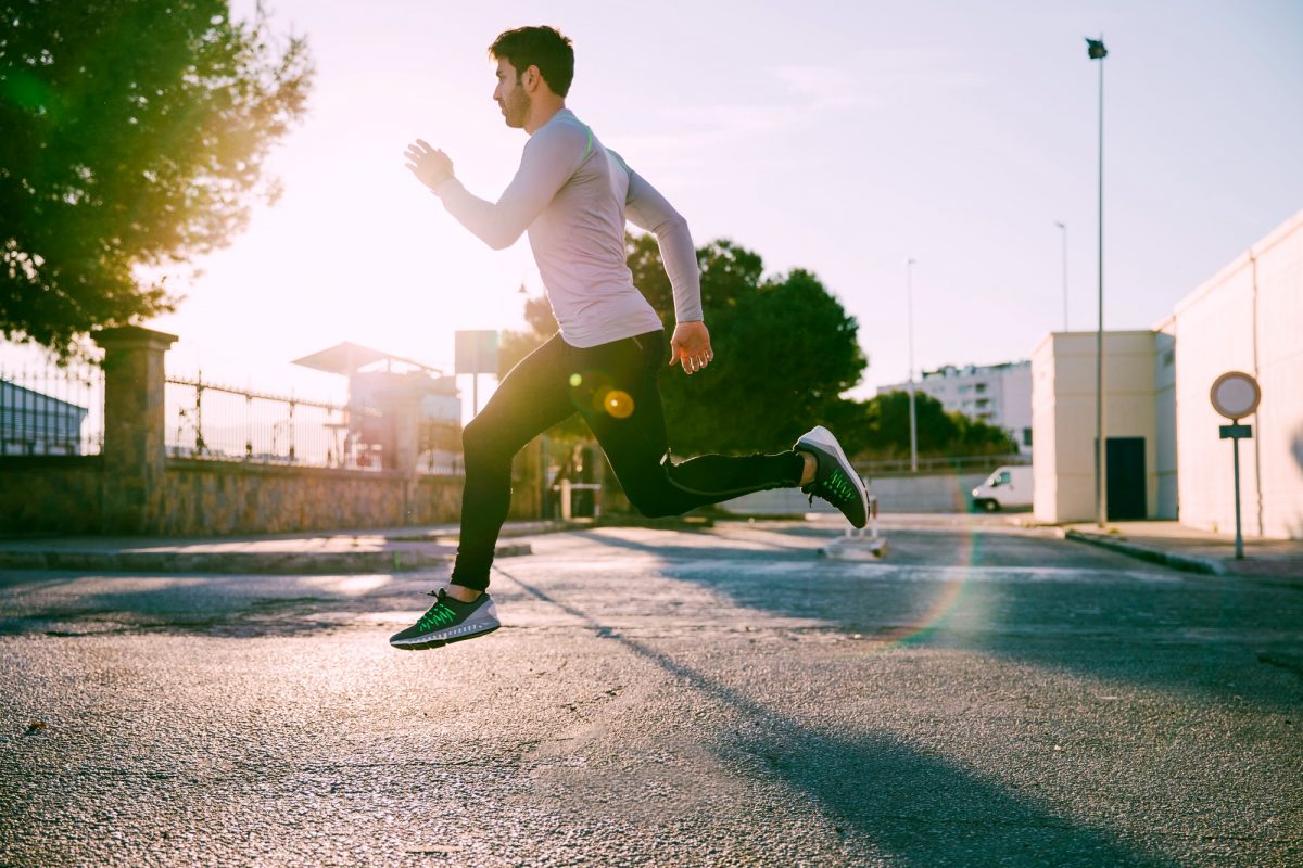 ออกกำลังกายให้ได้ประโยชน์เต็มร้อยด้วยการผสม 4 ประเภทของการออกกำลังกาย ผู้ชายวิ่งในชุดออกกำลังกายสลับกระโดด มีแสงกระทบจากดวงอาทิตย์