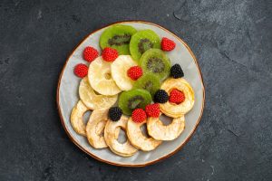 ผักผลไม้อบกรอบจัดวางในจานอย่างสวยงาม: สับปะรด กีวี่ เบอร์รี่